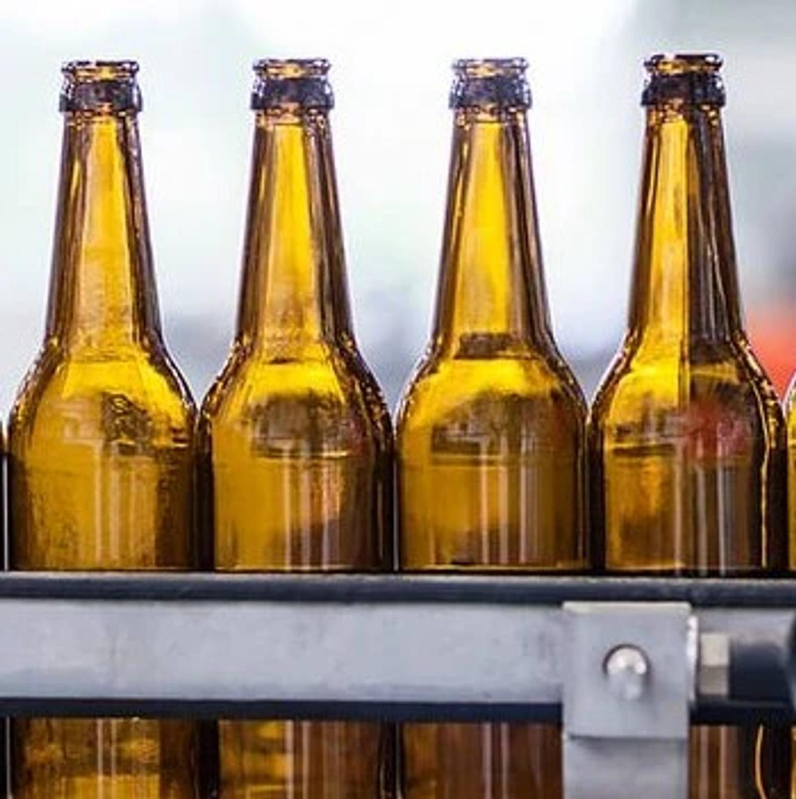 Four amber glass bottles on a bottling line