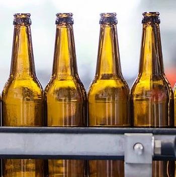 Four amber glass bottles on a bottling line