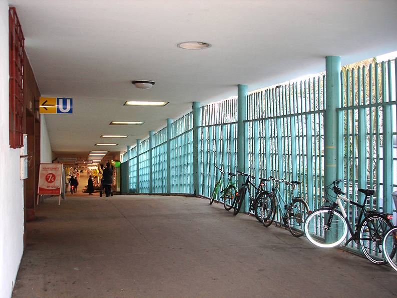 Überdachter Gang am U-Bahnhof Onkel Toms Hütte mit türkisfarbenen Stabgittern und abgestellten Fahrrädern