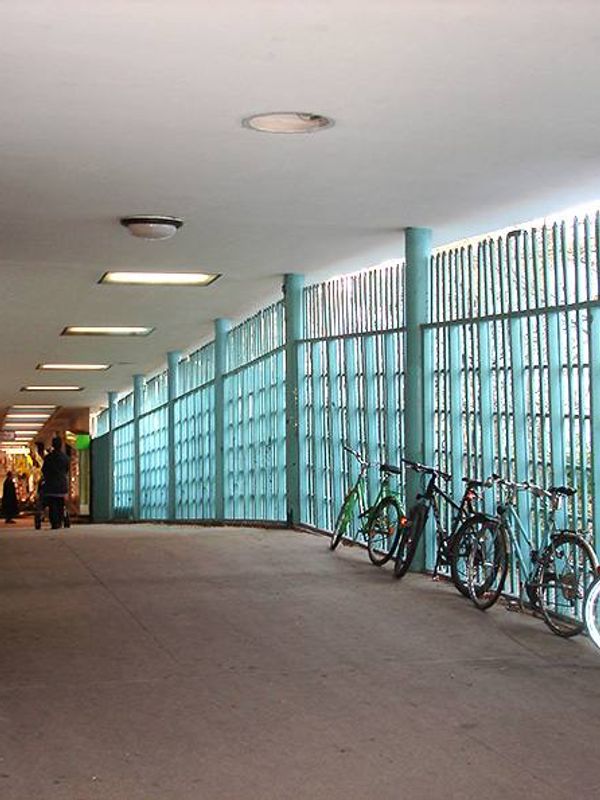 Überdachter Gang am U-Bahnhof Onkel Toms Hütte mit türkisfarbenen Stabgittern und abgestellten Fahrrädern