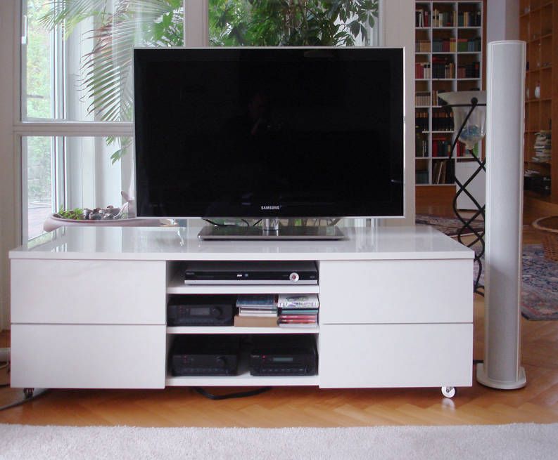 Weißes Lowboard auf Rollen mit offenen Fächern für Geräte, darauf ein Fernseher