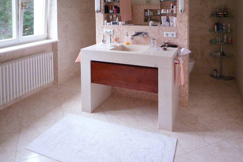 Waschtisch mit heller Platte und Unterschrank in einem gefliesten Bad