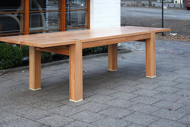 Große ausziehbare Massivholztafel mit kräftigen Vierkantbeinen, aufgestellt im Hof vor der Werkstatt