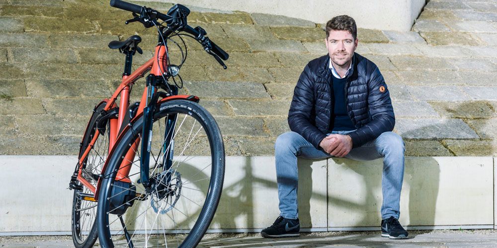 Man zit op een bankje naast een oranje fiets