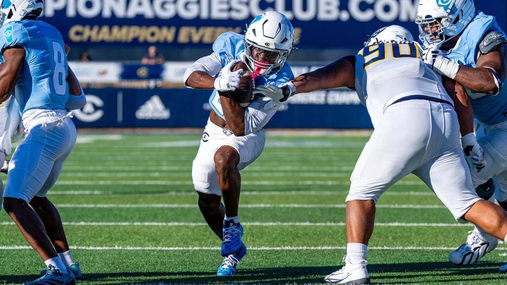 UC Davis running back Jordan Fisher carries the ball as a Northern Colorado defender wearing No. 90 reaches for the tackle at UC Davis Health Stadium