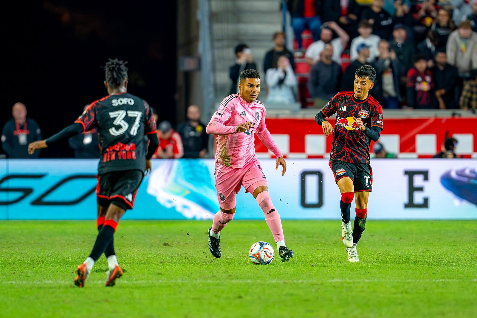 A Red Bull New York player in black and red carries the ball past an Inter Miami player in pink at Sports Illustrated Stadium on October 24, 2026.