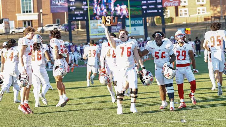 Nicholls players celebrate on the field, one holding up the NSU trophy, after a 31-27 win at Northwestern State on Oct. 24, 2026, at Turpin Stadium in Natchitoches, Louisiana.