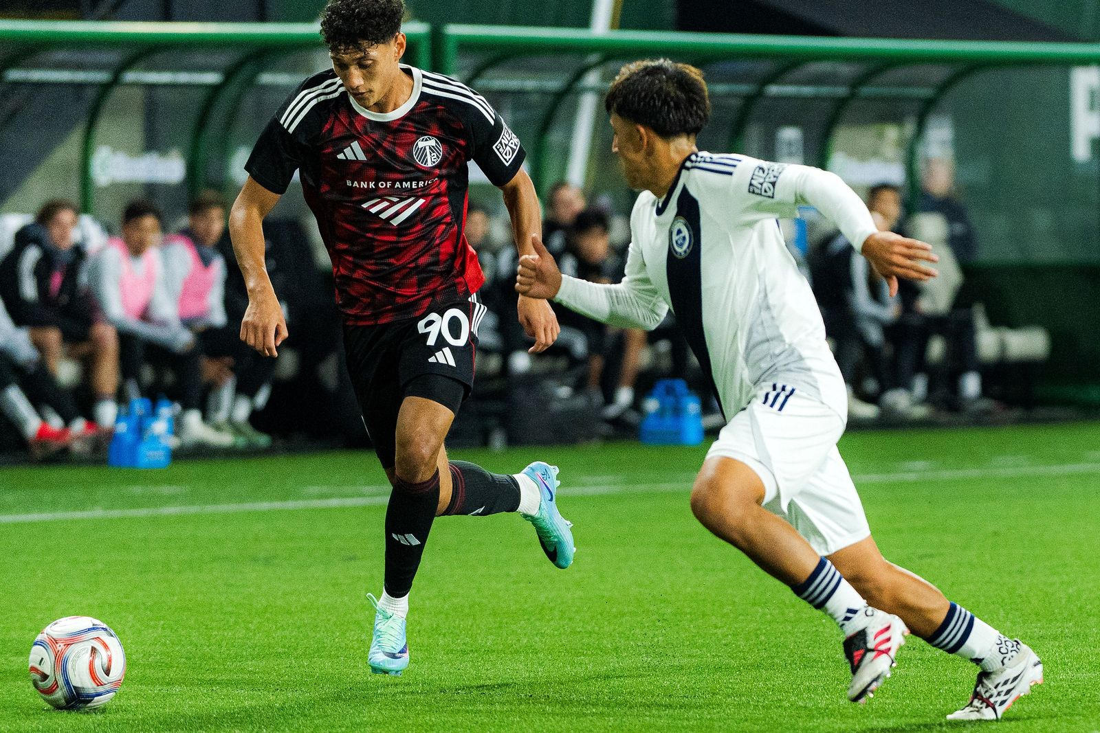 A Portland Timbers2 player in red and black dribbles under pressure from a Ventura County FC defender at Providence Park on October 25, 2026.
