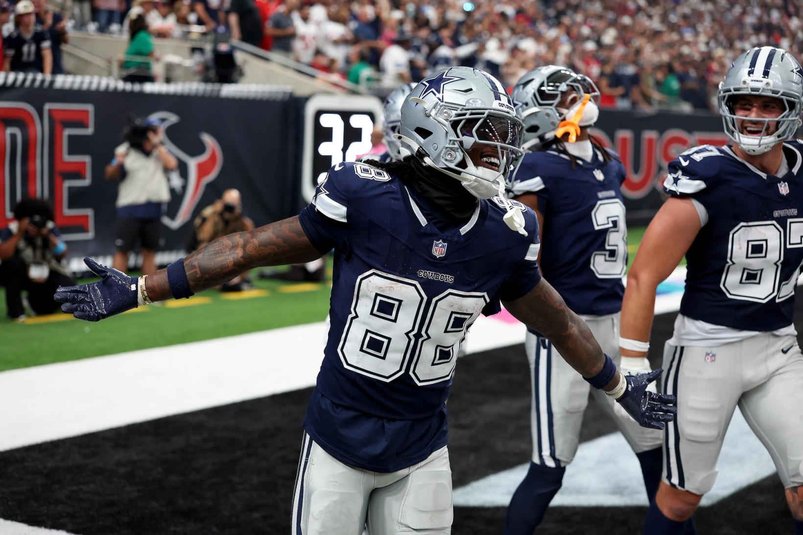 Dallas Cowboys wide receiver CeeDee Lamb (88) celebrates with his arms spread in the end zone as teammates, including tight end Jake Ferguson (87), join him against the Houston Texans.
