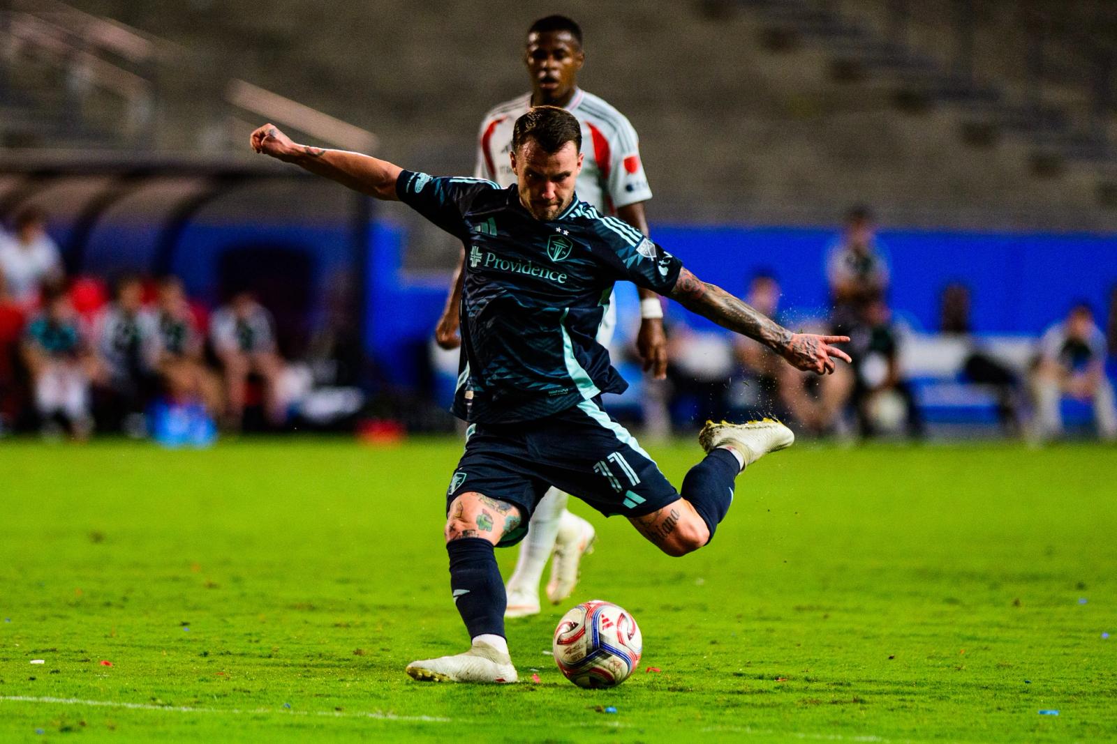 Seattle Sounders player kicks the ball as an FC Dallas player closes in at Toyota Stadium