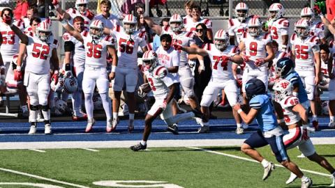 Dayton's LeRoy Lewis IV runs back a kickoff along the Dayton sideline as teammates in white celebrate and San Diego players in light blue chase on Oct. 24, 2026