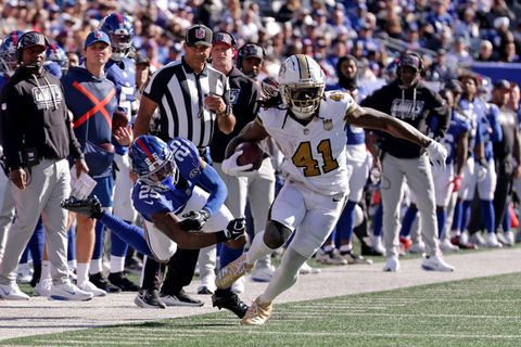 New Orleans Saints running back Alvin Kamara (41) carries the ball along the sideline past a diving New York Giants defender at MetLife Stadium.