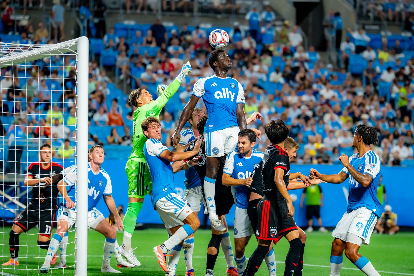 A Charlotte FC player rises to head the ball in a crowded D.C. United penalty area during the August 22, 2026 match at Bank of America Stadium.