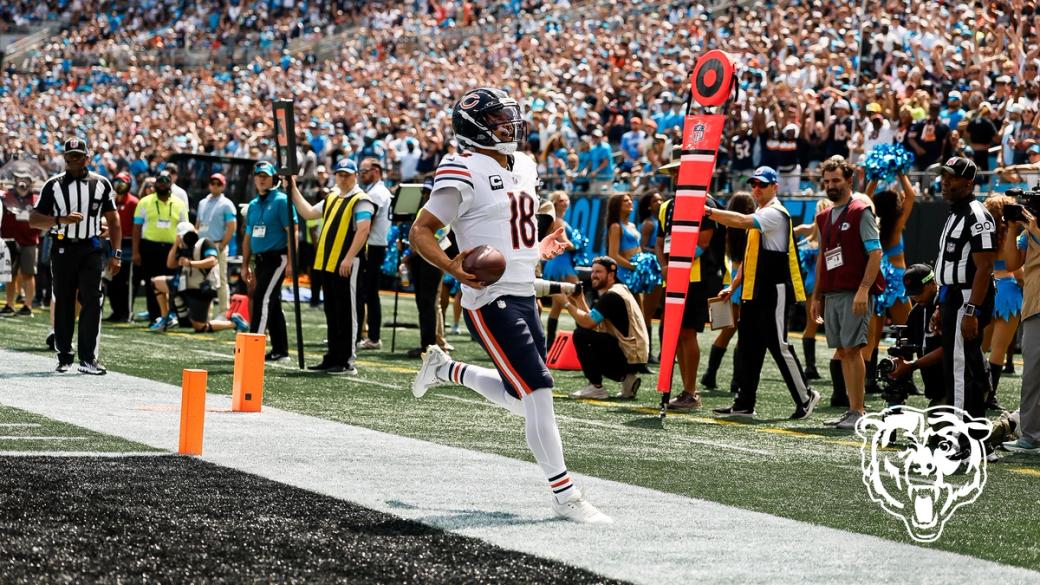 Chicago Bears quarterback Caleb Williams (18) carries the football past the goal-line pylons at Bank of America Stadium as fans in the stands cheer