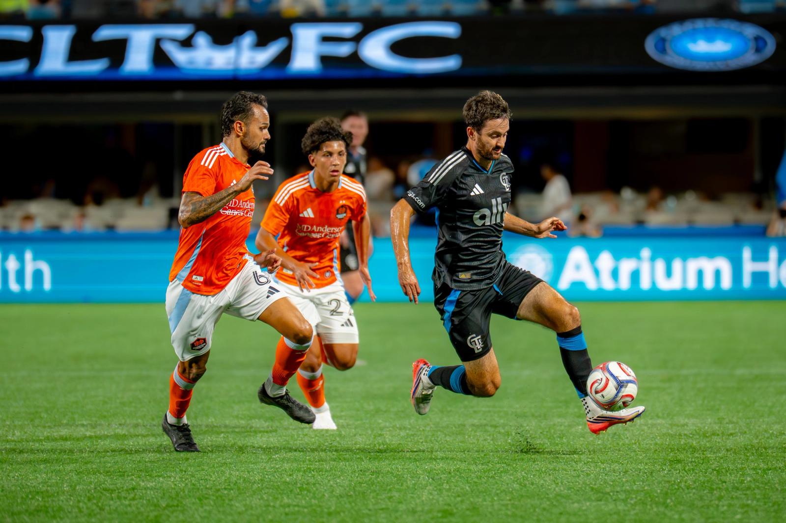Charlotte FC player controls the ball under pressure from Houston Dynamo defenders. Photo Credit: Arturo Rosales Sevilla/Undrafted