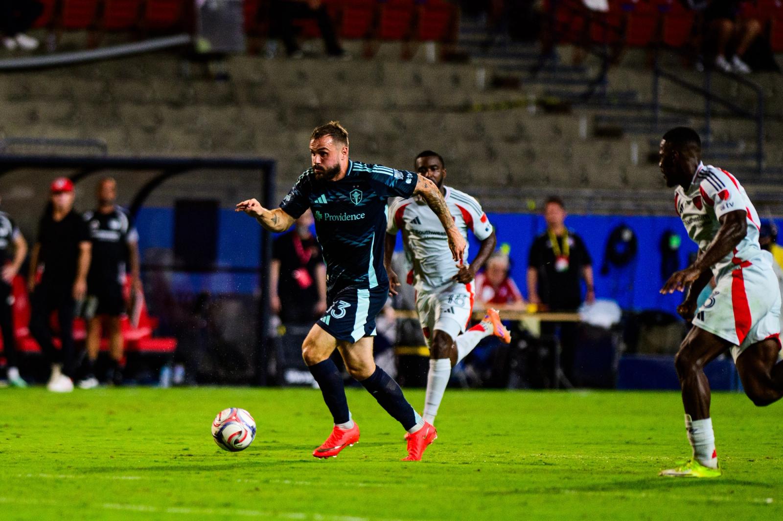 Seattle Sounders player dribbles as FC Dallas players chase at Toyota Stadium