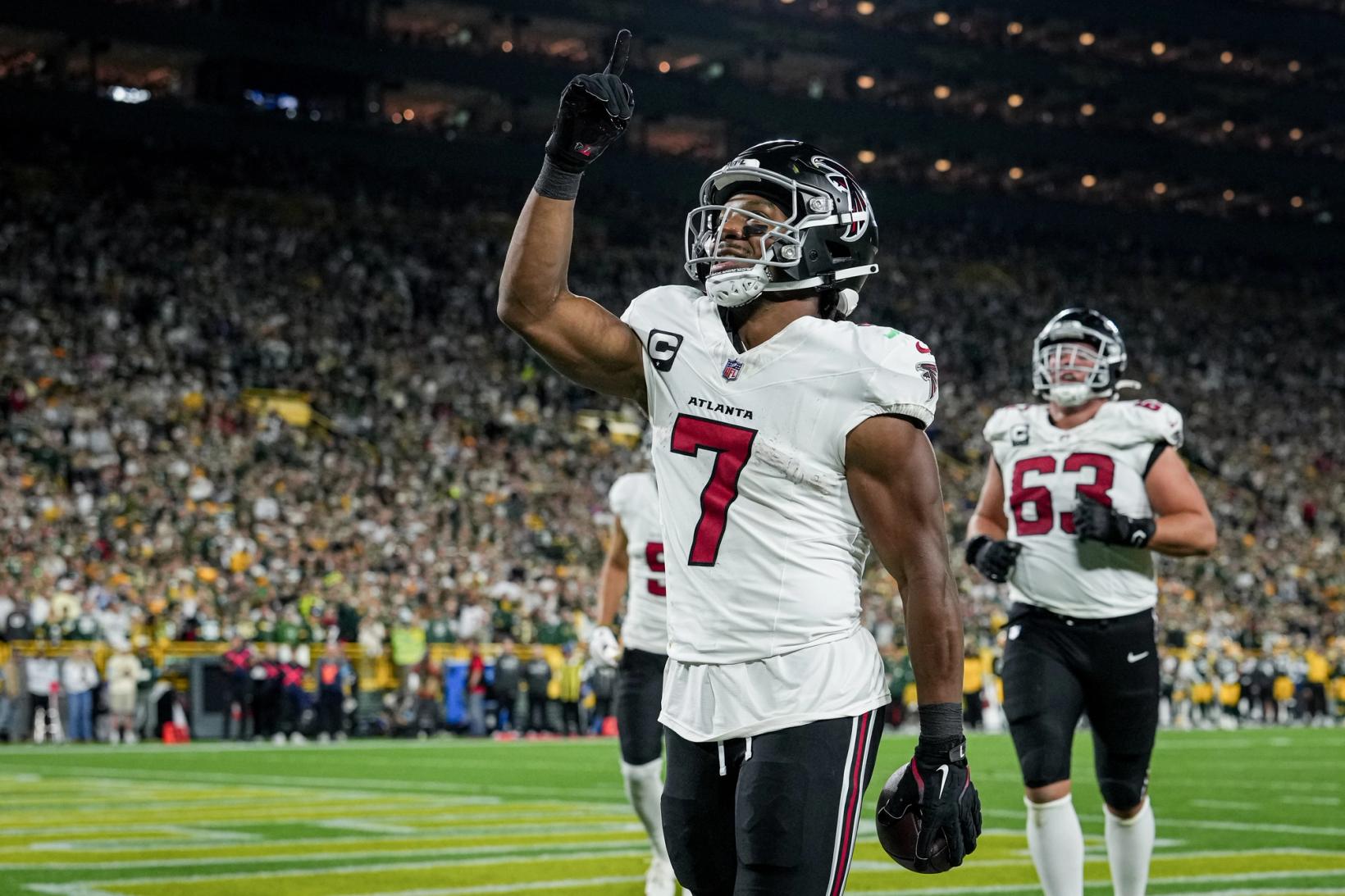 Atlanta Falcons running back Bijan Robinson (7) points skyward on the field at Lambeau Field as a Falcons teammate jogs up behind him