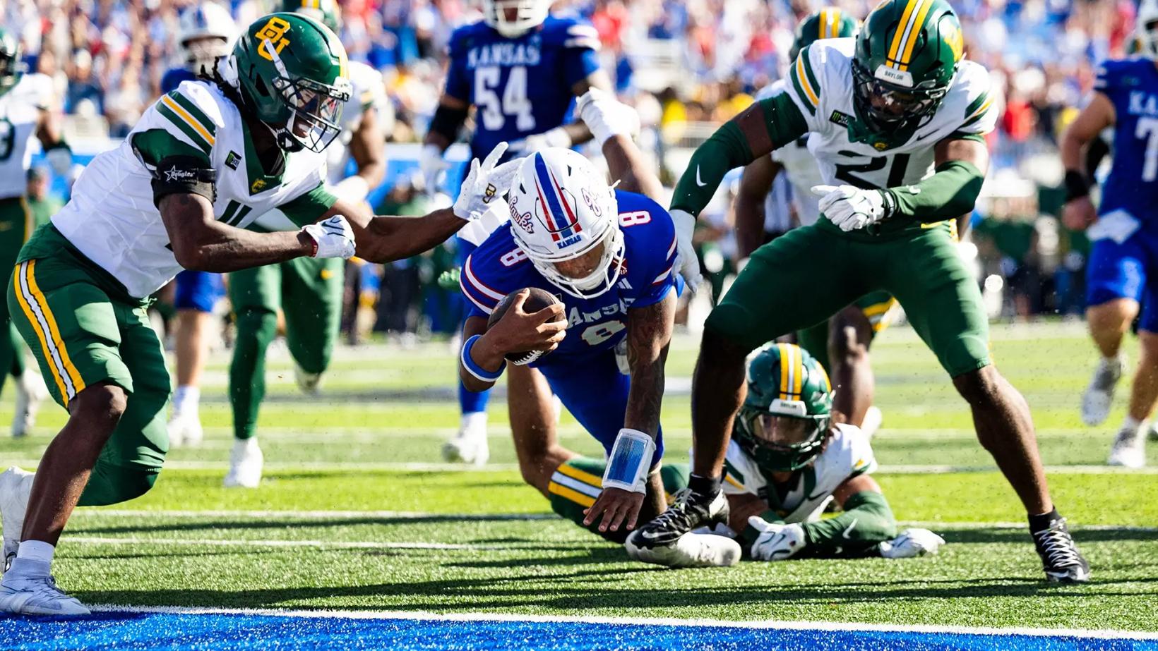 Kansas quarterback Isaiah Marshall dives toward the goal line between Baylor defenders on his late touchdown run.