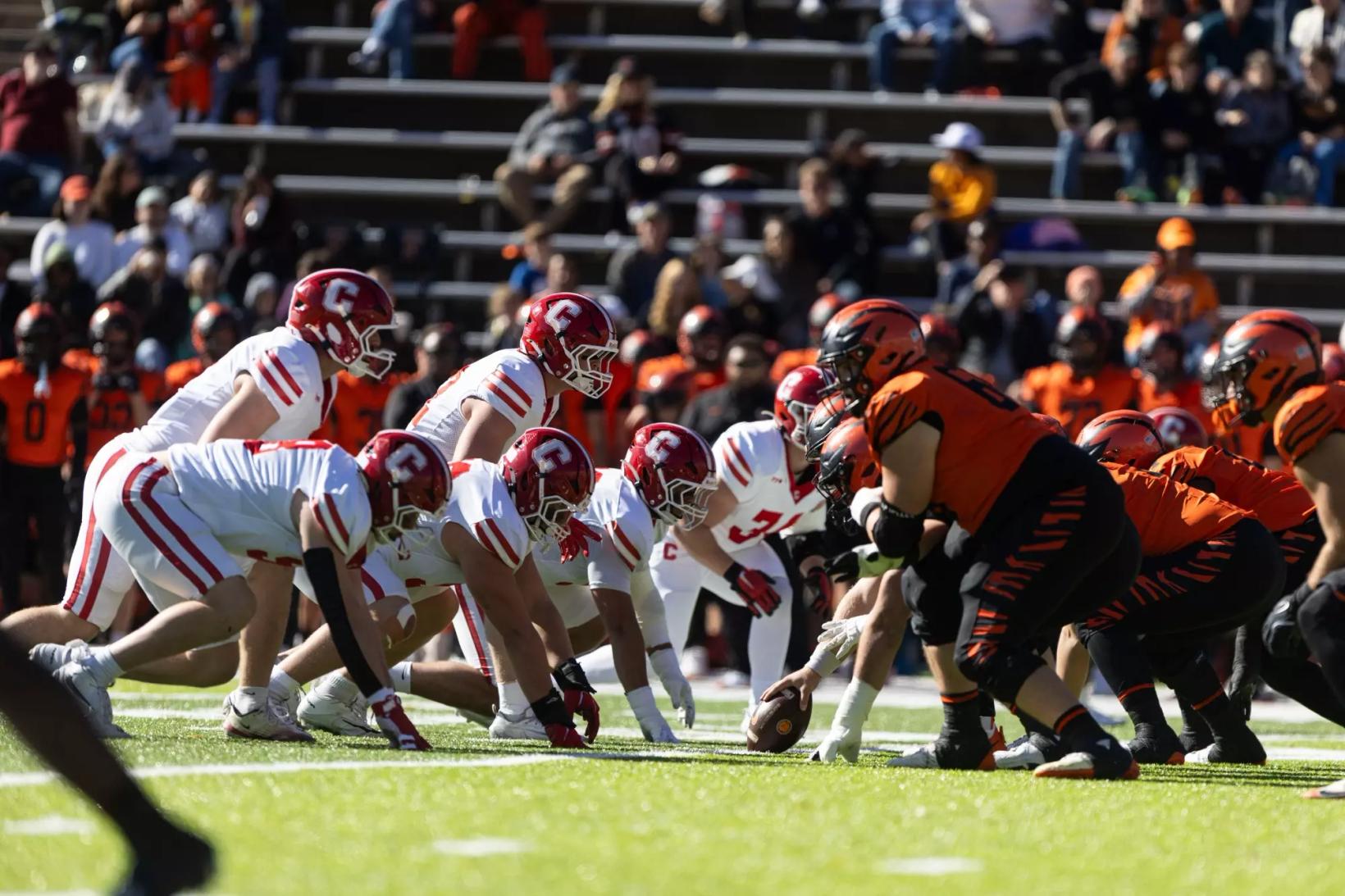 Cornell's defense in white and red lines up across from Princeton's offense in orange and black before a snap at Princeton Stadium on Oct. 31, 2026, in Princeton's 21-20 win.