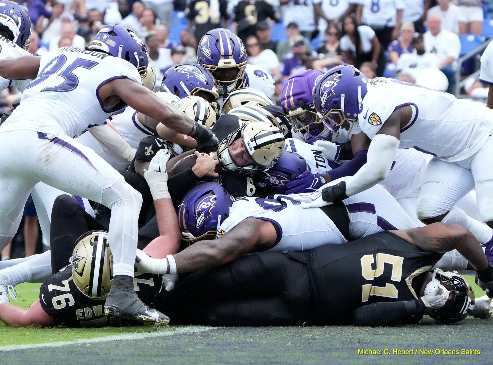A New Orleans Saints player wearing No. 6 holds the football under a pile of Baltimore Ravens defenders near the goal line at M&T Bank Stadium