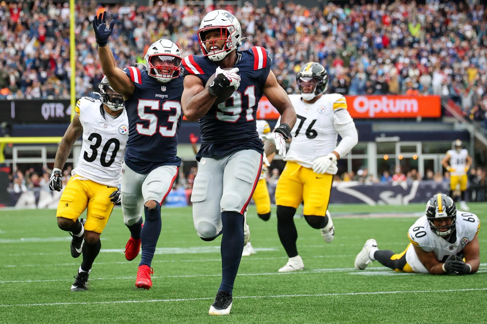 New England Patriots linebacker Elijah Ponder (91) carries the football toward the end zone as a teammate raises his arm and Pittsburgh Steelers players trail the play at Gillette Stadium