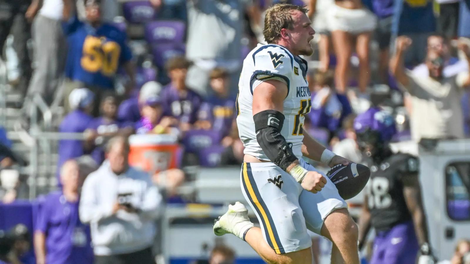 West Virginia linebacker Ben Cutter, in a white road jersey, celebrates with the football after recovering TCU's late fumble at Amon G. Carter Stadium in Fort Worth, Texas, on Oct. 24, 2026