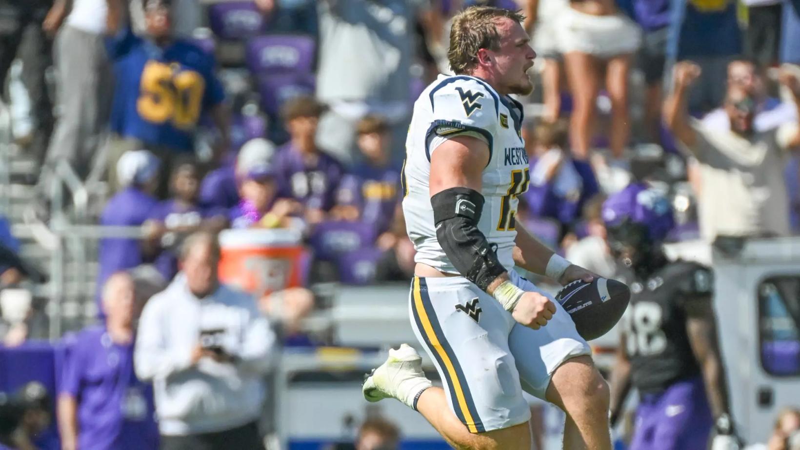 West Virginia linebacker Ben Cutter, in a white road jersey, celebrates with the football after recovering TCU's late fumble at Amon G. Carter Stadium in Fort Worth, Texas, on Oct. 24, 2026