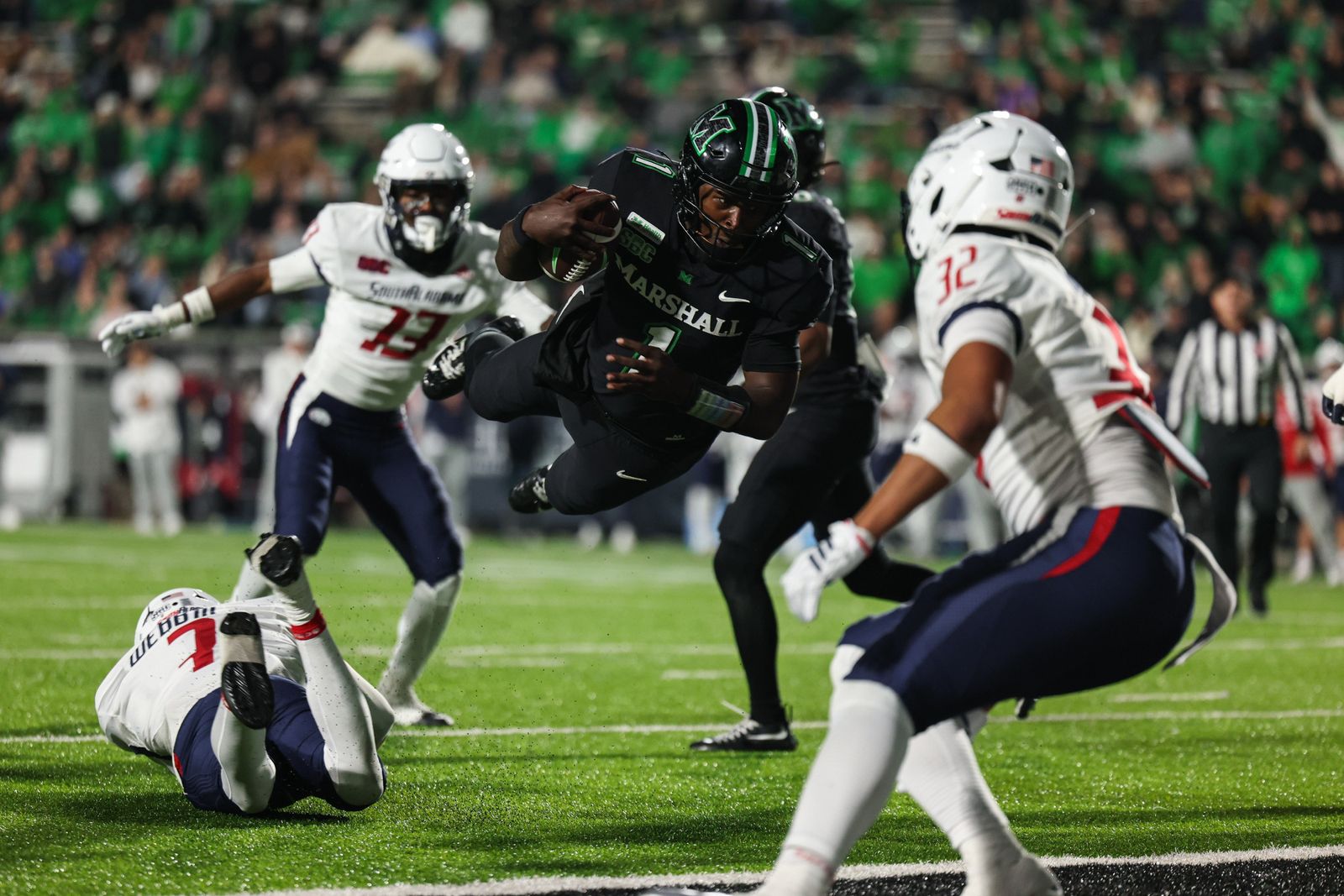 A Marshall ball carrier in a black uniform dives toward the goal line past South Alabama defenders at Joan C. Edwards Stadium on Oct. 20, 2026