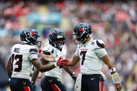 Houston Texans quarterback C.J. Stroud (7) celebrates with wide receiver Jaylin Noel (13) and another teammate in front of a packed stadium crowd.