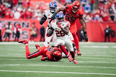 New York Giants running back Devin Singletary (26) carries the ball past a Houston Texans defender sprawled on the turf as another Texans defender gives chase at Reliant Stadium.