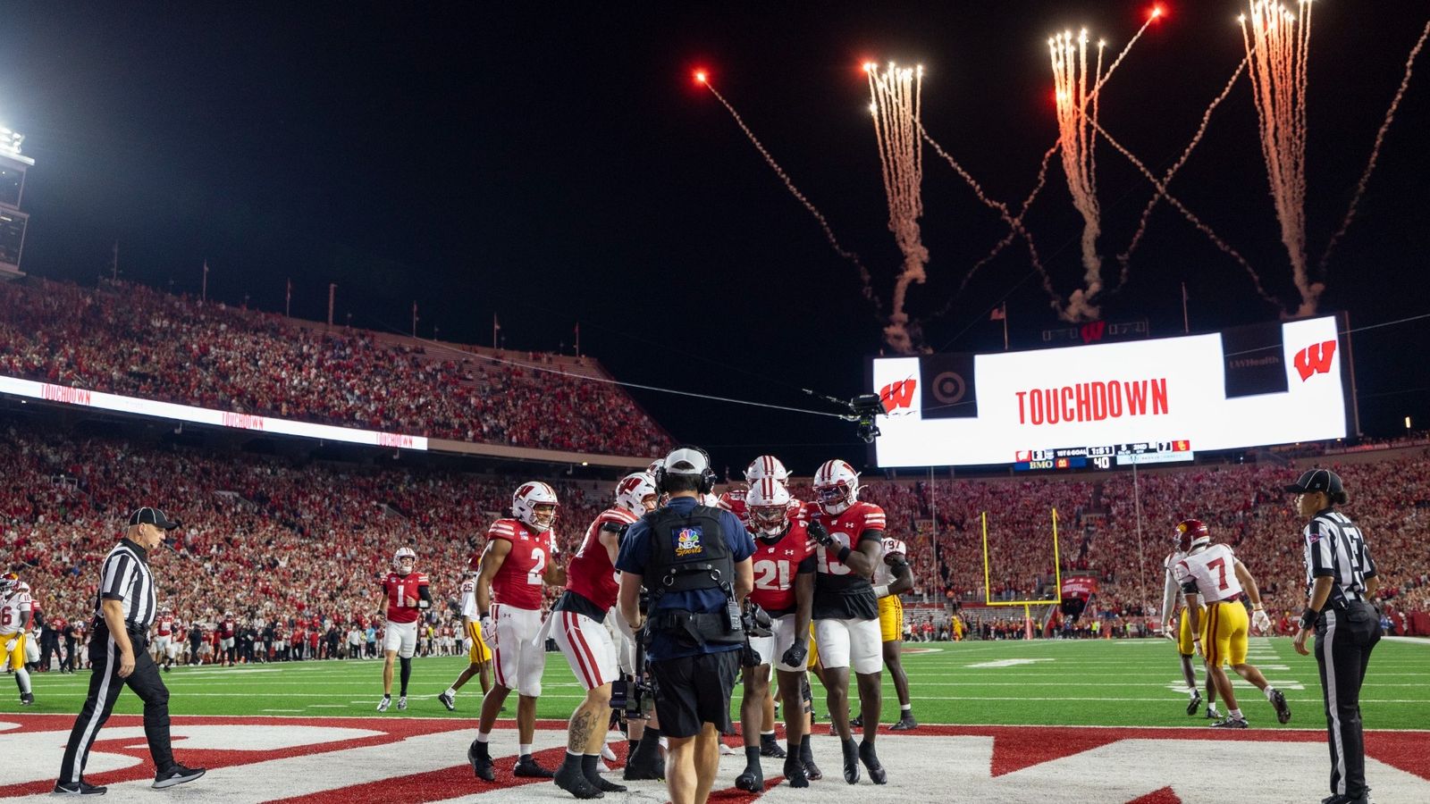 Wisconsin players in red jerseys celebrate a touchdown in the end zone as fireworks go off and the Camp Randall Stadium video board reads Touchdown during the Badgers' 24-7 win over USC on Oct. 24, 2026, in Madison