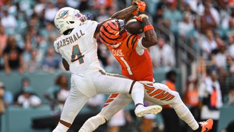 Cincinnati Bengals wide receiver Ja'Marr Chase (1) hauls in a pass at Hard Rock Stadium with Miami Dolphins cornerback Jason Marshall Jr. (4) draped on him from behind.