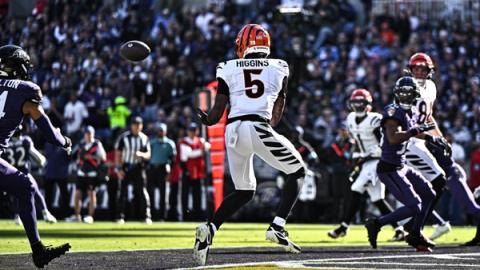 Cincinnati Bengals wide receiver Tee Higgins (5) looks the ball into his hands near the goal line as Baltimore Ravens defenders close in at M&T Bank Stadium.