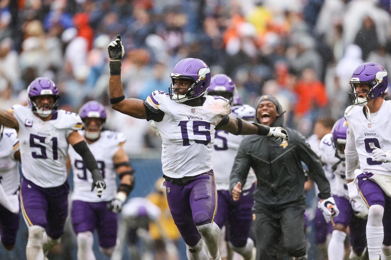 Minnesota Vikings linebacker Dallas Turner (15) points skyward as teammates, including Blake Cashman (51), run onto the field to celebrate at Soldier Field.