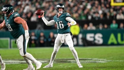 Philadelphia Eagles quarterback Tanner McKee, wearing No. 16, winds up to throw as an Eagles offensive lineman blocks beside him.