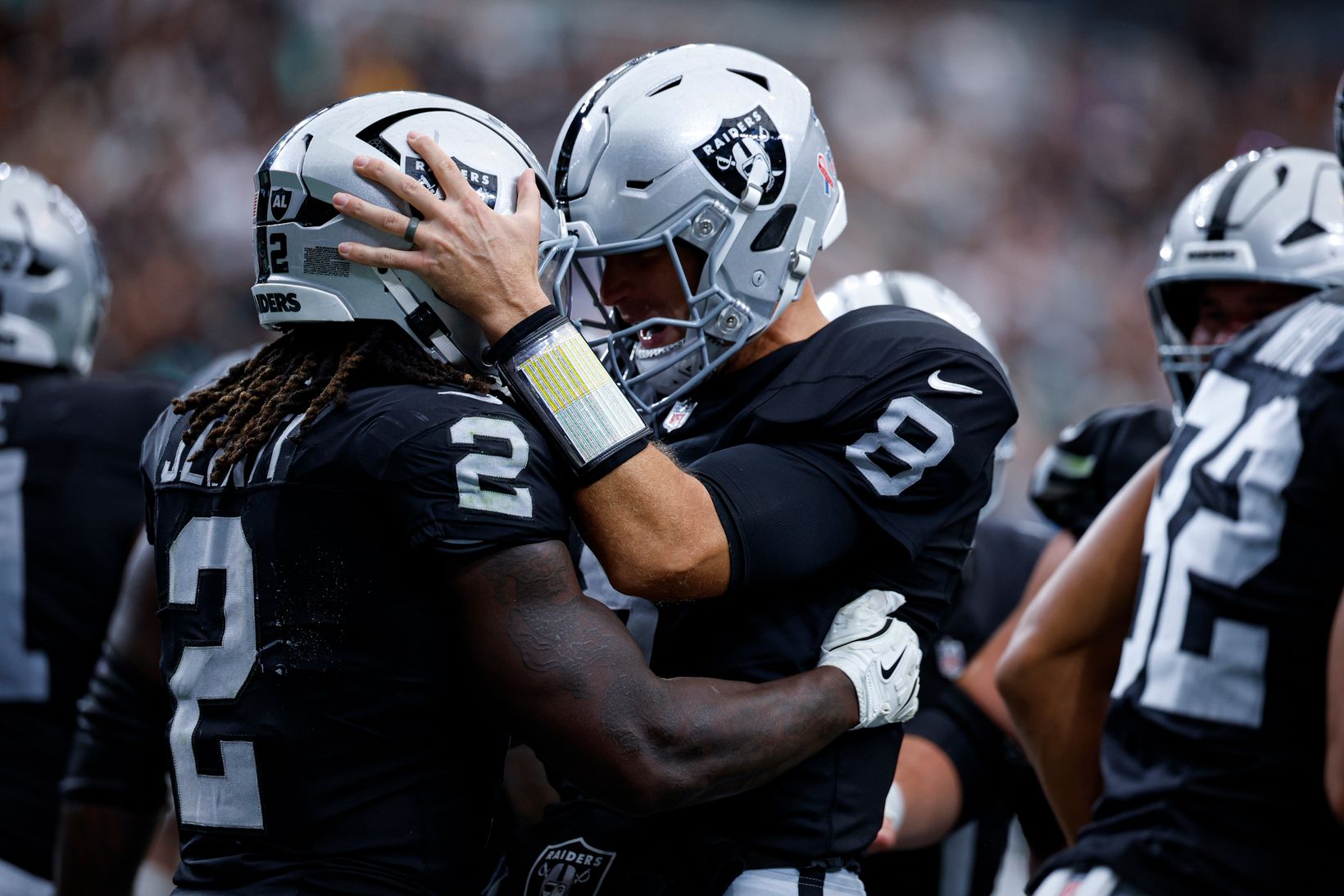 Las Vegas Raiders quarterback Kirk Cousins (8) puts his hand on the helmet of running back Ashton Jeanty (2) as they celebrate with teammates.