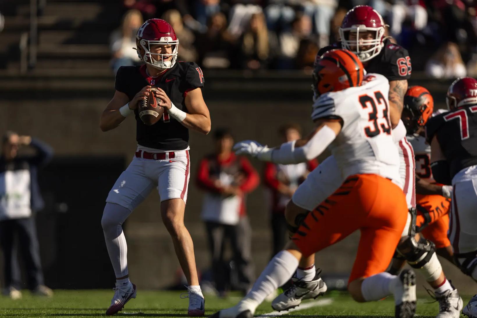 Harvard quarterback Charlie Smith, No. 14 in black, sets to throw as a Princeton defender is held up during Harvard's 35-7 win over Princeton at Harvard Stadium on Oct. 24, 2026