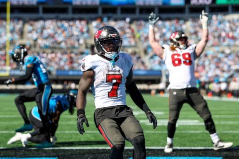 Tampa Bay Buccaneers running back Bucky Irving (7) stands near the goal line as a Buccaneers lineman raises both arms behind him at Bank of America Stadium.