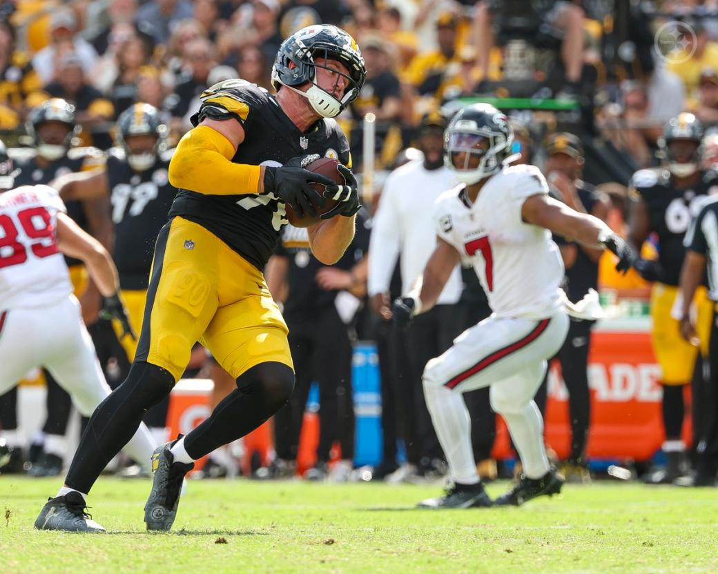 Pittsburgh Steelers linebacker T.J. Watt (90) secures the football with both hands as an Atlanta Falcons player trails the play at Acrisure Stadium