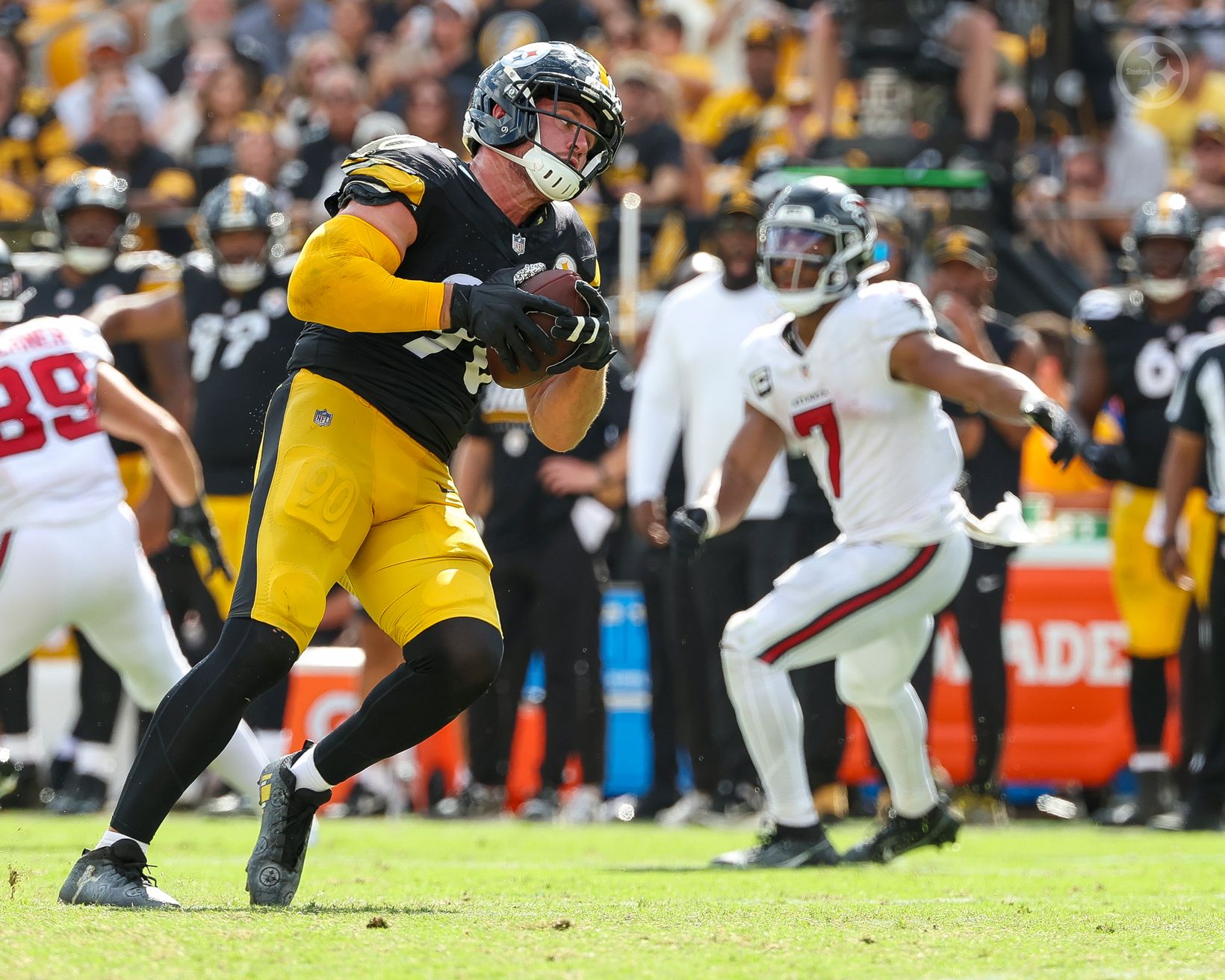 Pittsburgh Steelers linebacker T.J. Watt (90) secures the football with both hands as an Atlanta Falcons player trails the play at Acrisure Stadium