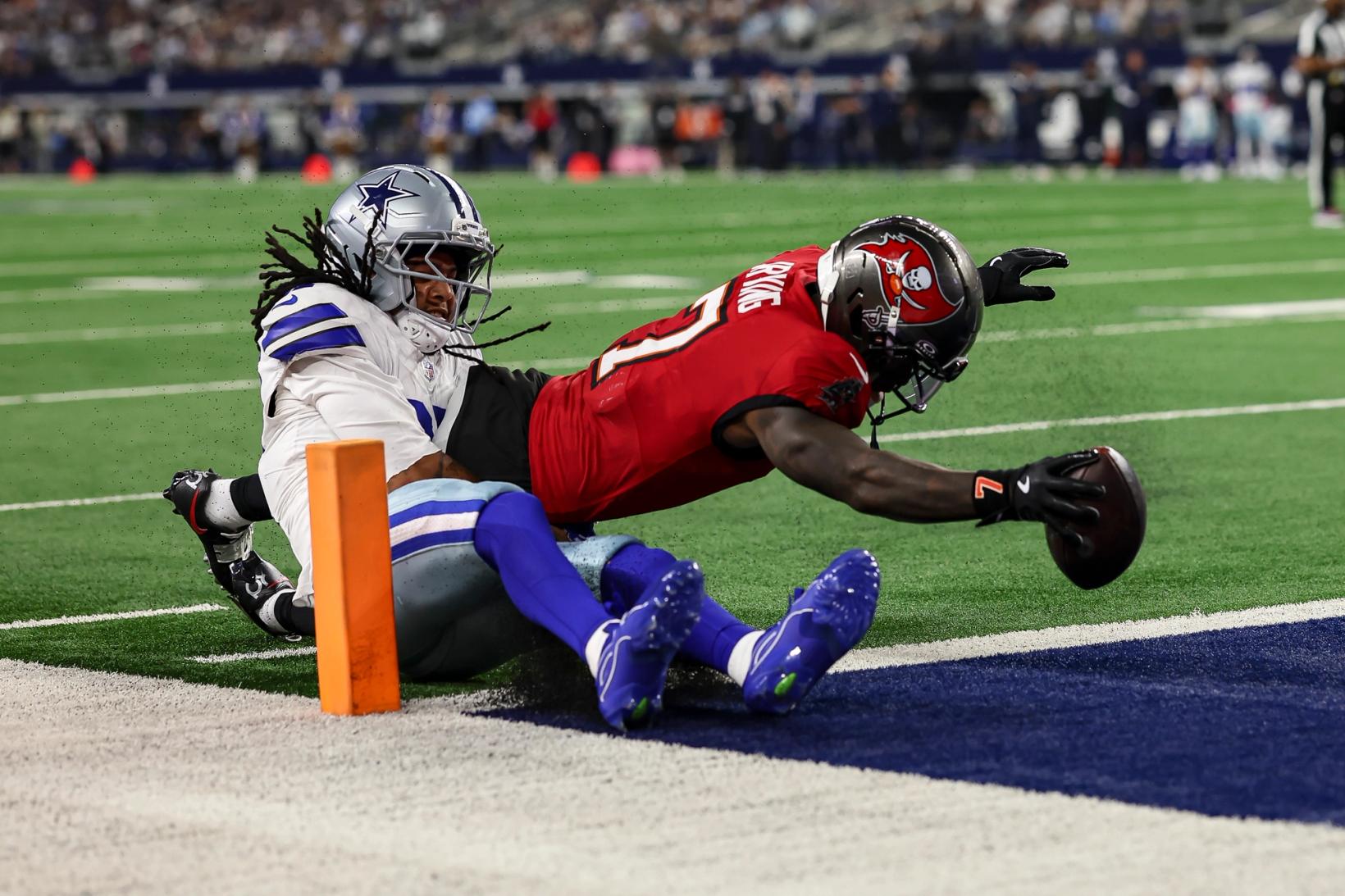 Tampa Bay Buccaneers running back Bucky Irving (7) stretches the ball toward the goal line beside the pylon as a Dallas Cowboys defender hangs onto him at AT&T Stadium