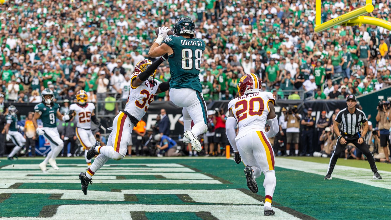 Philadelphia Eagles tight end Dallas Goedert (88) leaps to catch a pass between two Washington Commanders defenders in the end zone at Lincoln Financial Field