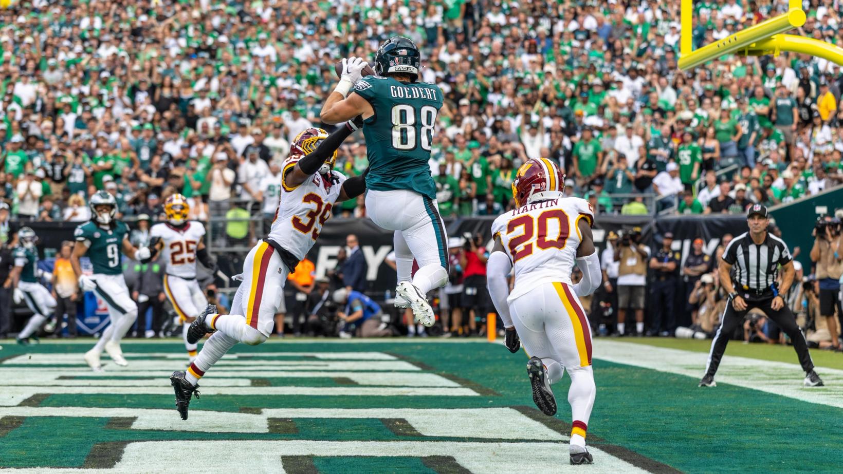Philadelphia Eagles tight end Dallas Goedert (88) leaps to catch a pass between two Washington Commanders defenders in the end zone at Lincoln Financial Field