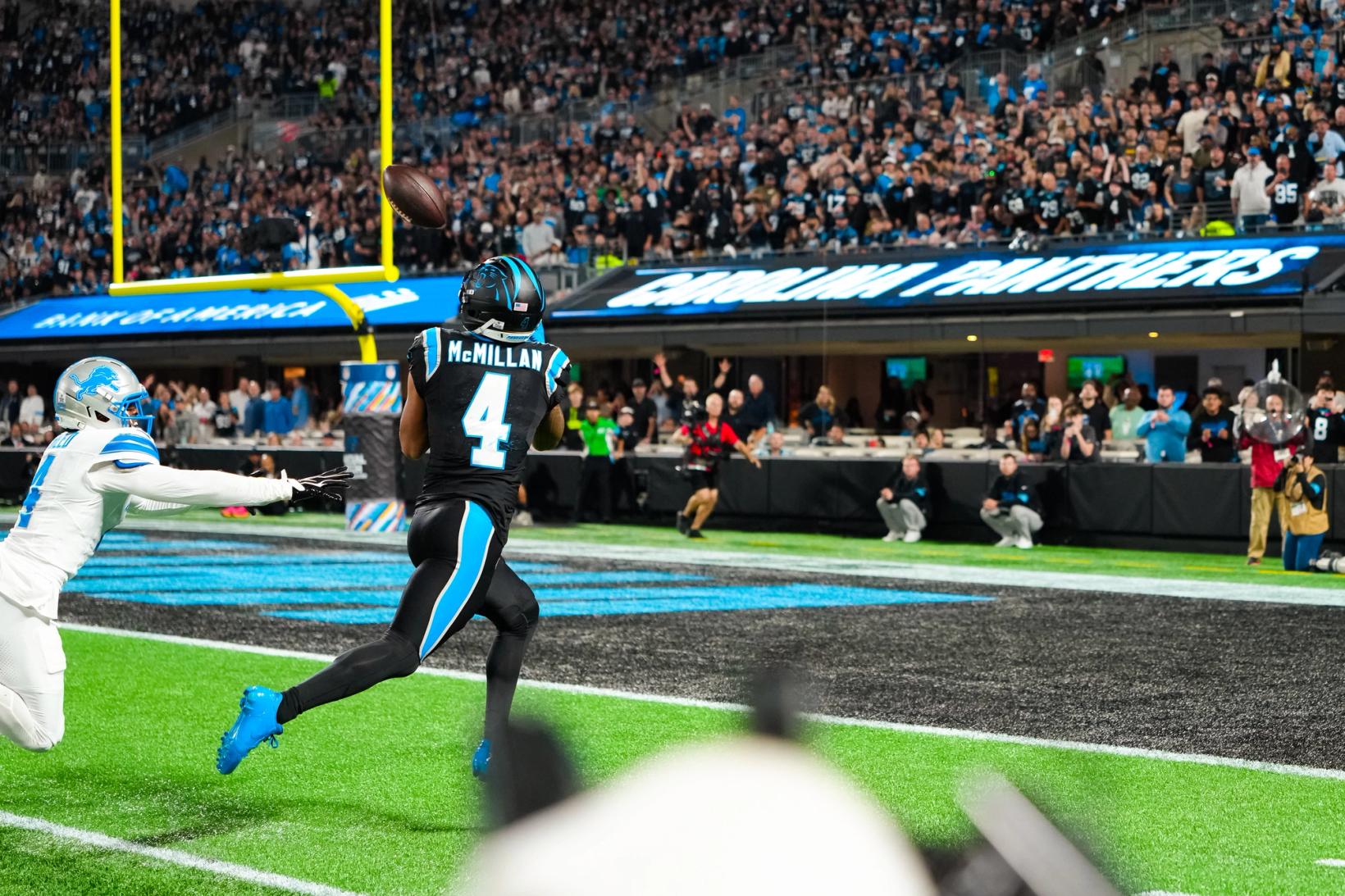 Carolina Panthers' Tetairoa McMillan (4) tracks a pass in the air near the end zone as a Detroit Lions defender dives behind him at Bank of America Stadium