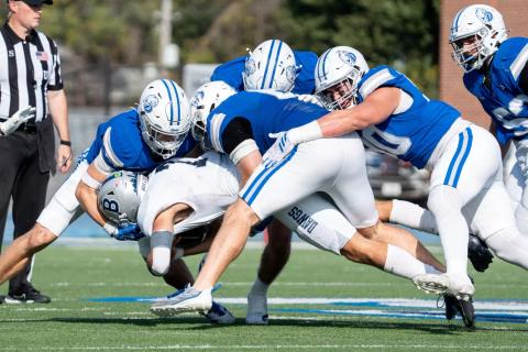 Drake defenders in blue jerseys and white helmets gang-tackle a Butler ball carrier during a home game earlier this season (file photo).
