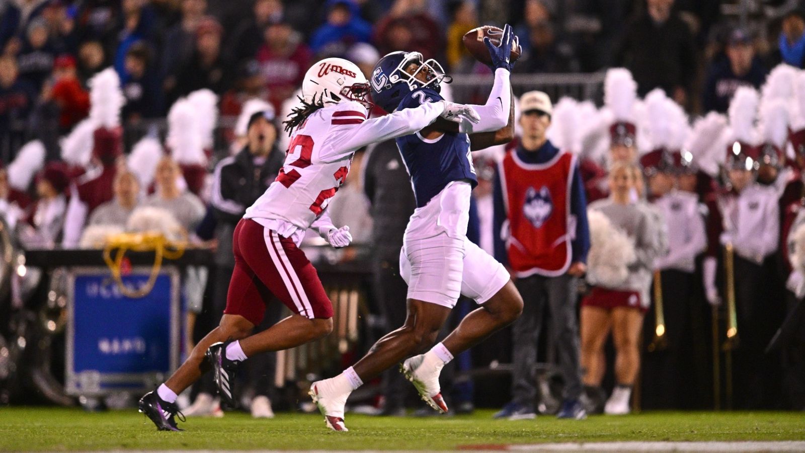 UConn wide receiver JD Willoughby, in a navy jersey, reaches up to catch a pass over a UMass defender in white during the Huskies' 35-16 win over UMass on Oct. 23, 2026.
