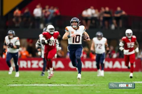 Denver Broncos quarterback Bo Nix (10) runs with the ball through open field as Arizona Cardinals defenders and Broncos teammates trail behind him at State Farm Stadium.