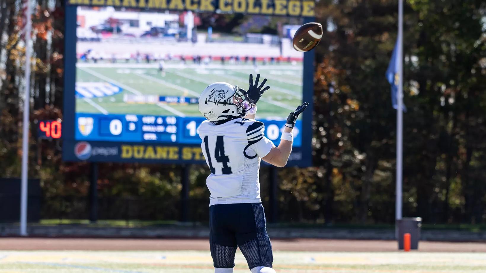 New Hampshire receiver Ryan Ricketti, No. 14, reaches for a pass in front of the scoreboard at Merrimack's Duane Stadium