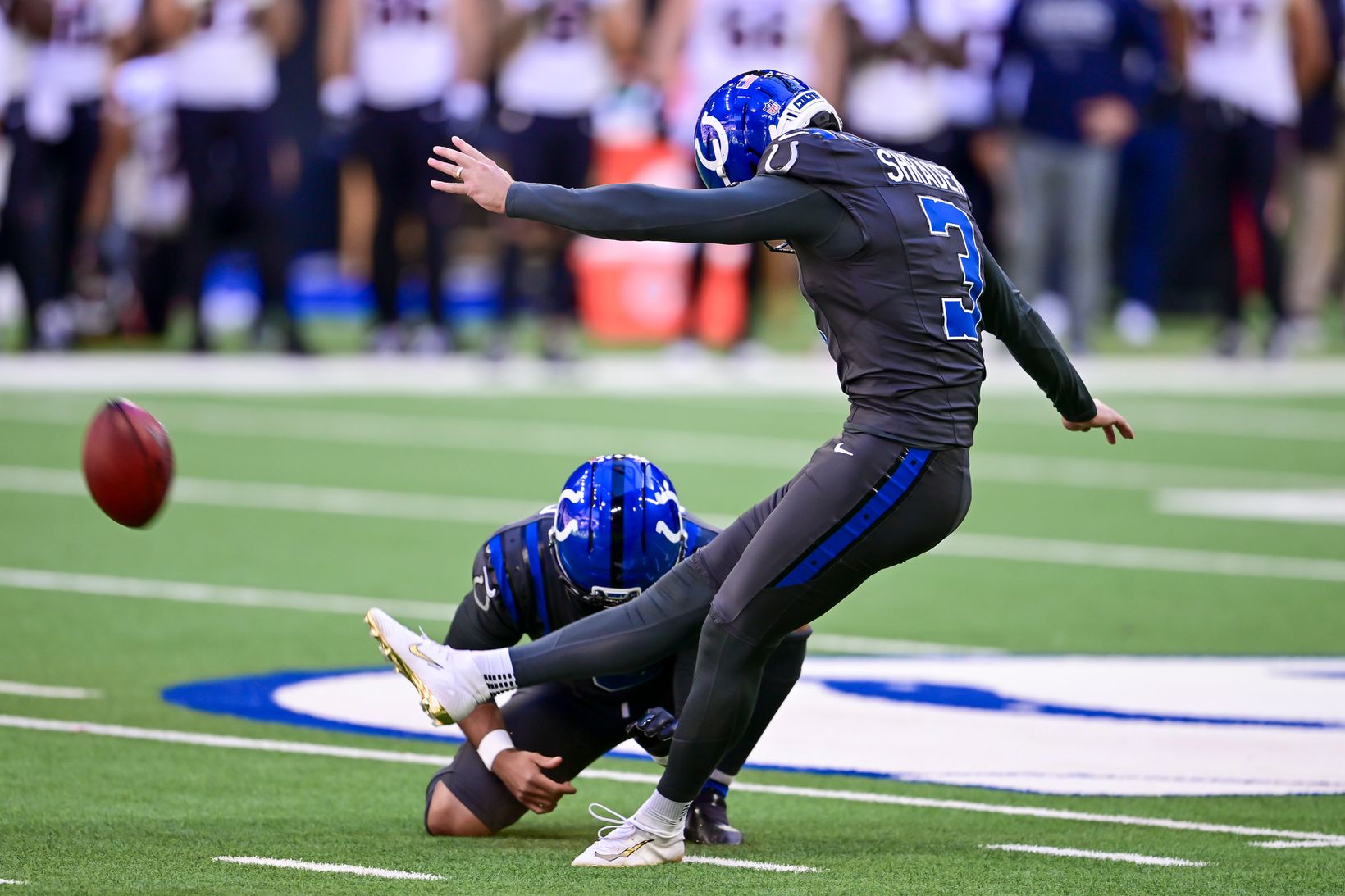 Indianapolis Colts kicker Spencer Shrader (3) follows through on a kick from a kneeling holder as the ball flies away at Lucas Oil Stadium