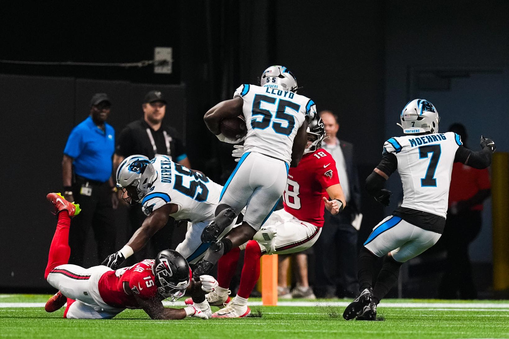 Carolina Panthers linebacker Devin Lloyd (55) carries the ball as teammate Bobby Okereke (58) dives toward a fallen Atlanta Falcons player and another Falcon trails behind.